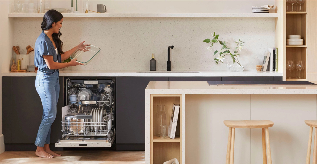 woman holding a casserole dish by the dishwasher in a modern minimalist kitchen